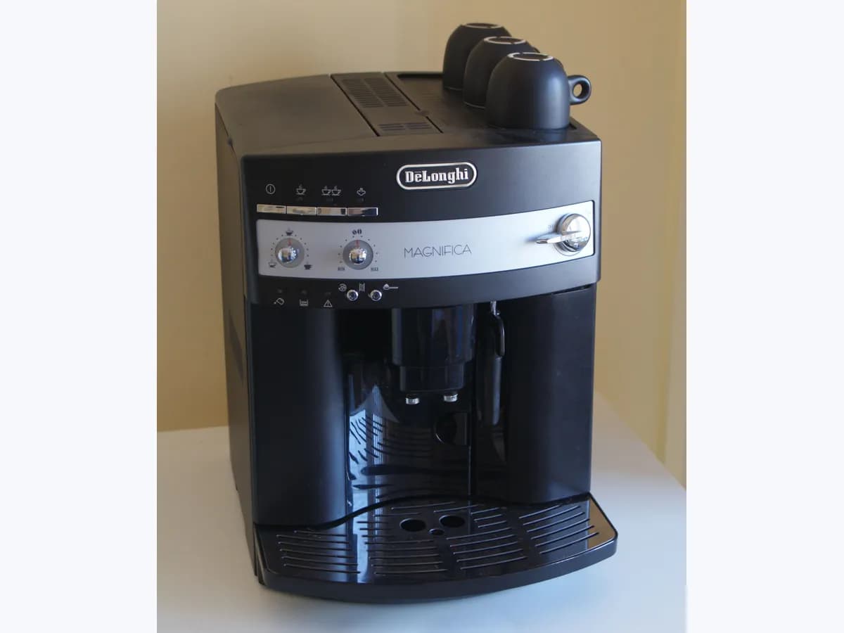 Cafetera superautomática De'Longhi Magnifica negra con tazas en la parte superior