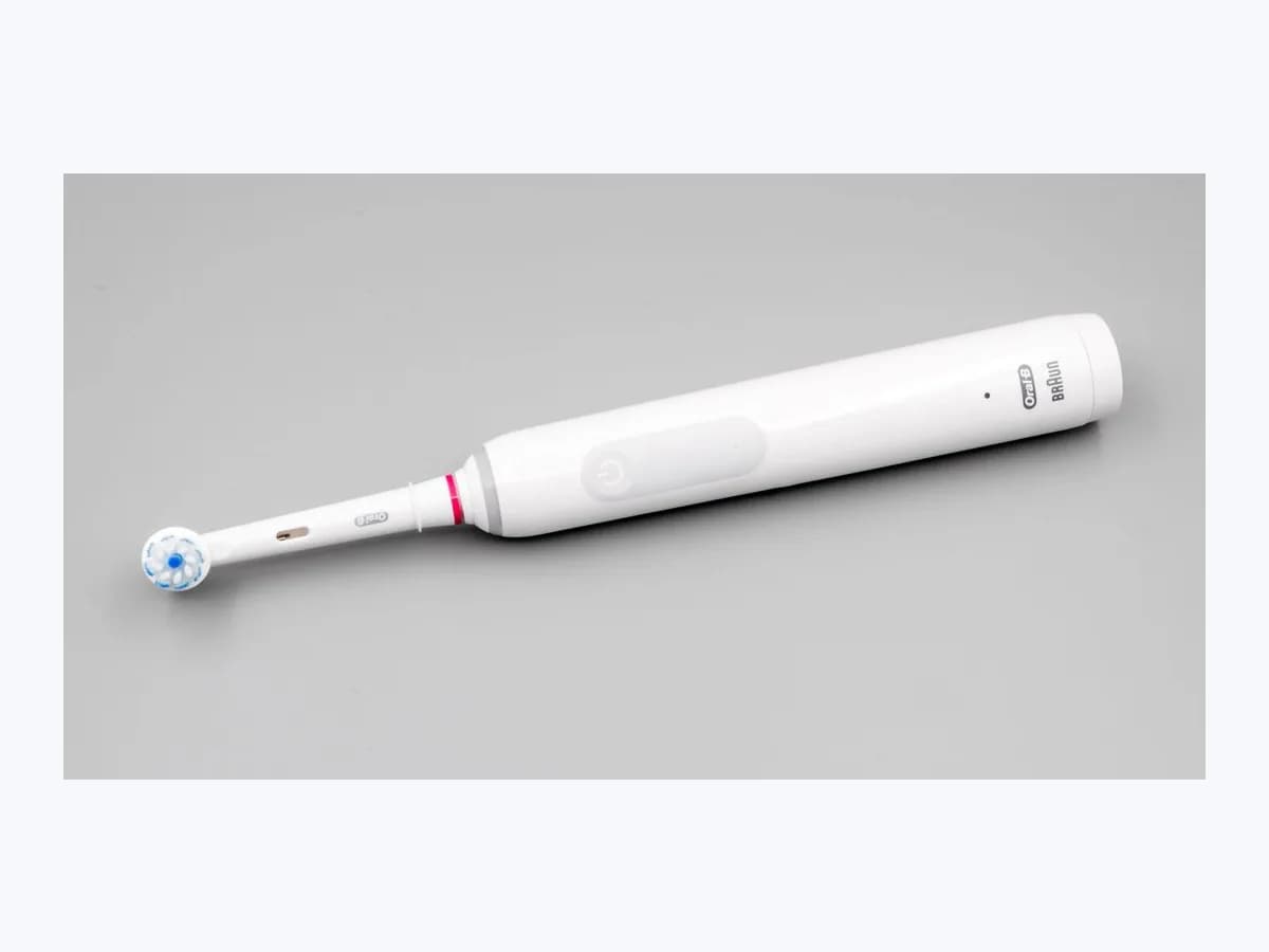 Rechargeable Oral-B Pro 3 3000 electric toothbrush with white handle and round brush head on a plain grey background