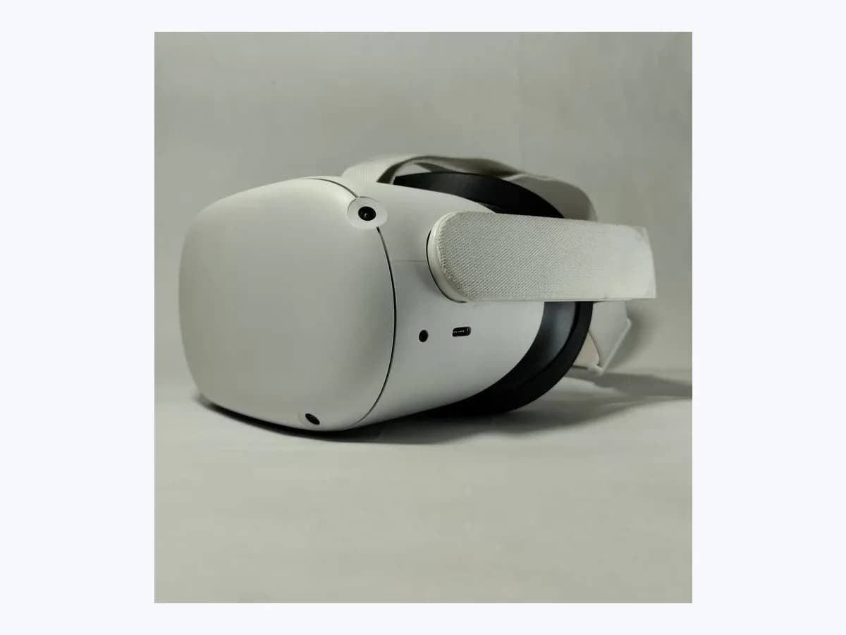 White Meta Quest 2 virtual reality headset seen in three-quarter profile on a plain light grey background