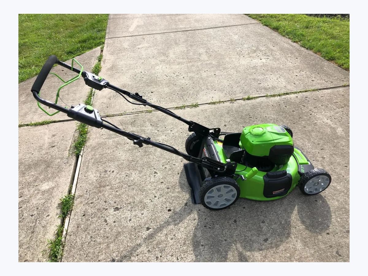 Greenworks 40 V 21-inch self-propelled cordless lawn mower on a pavement with grass on both sides