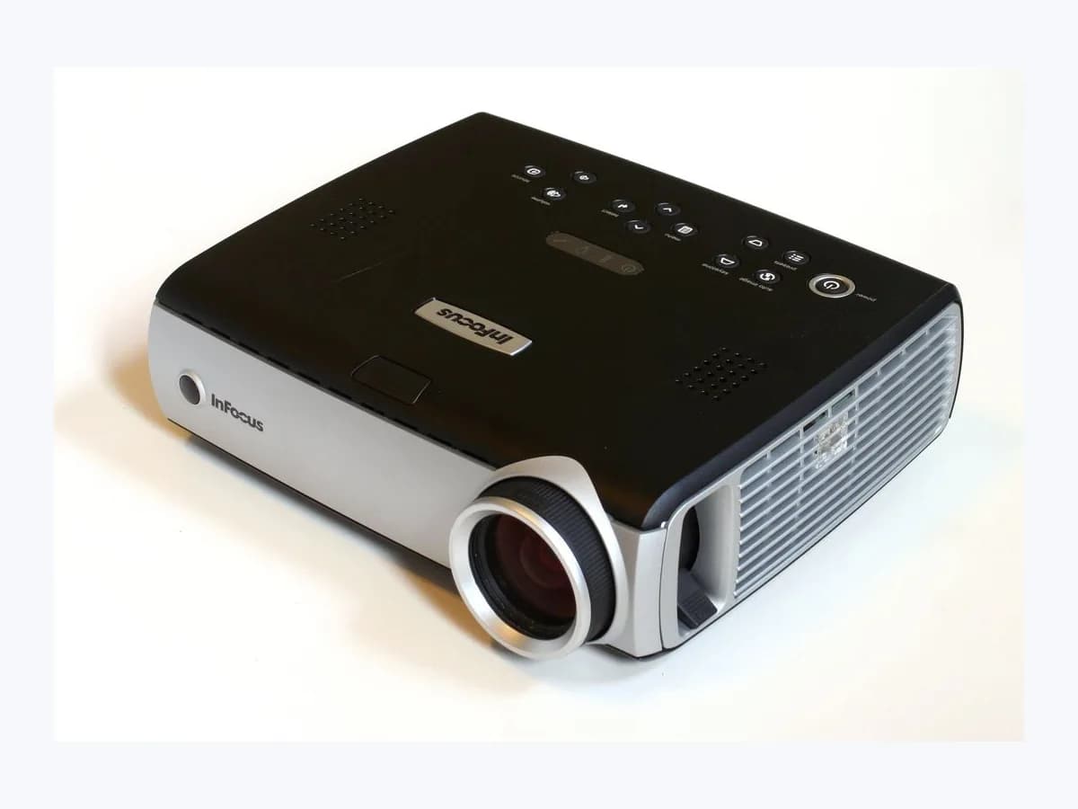 InFocus digital video projector on a plain white background showing the front lens, side ventilation grille, and top button and indicator panel