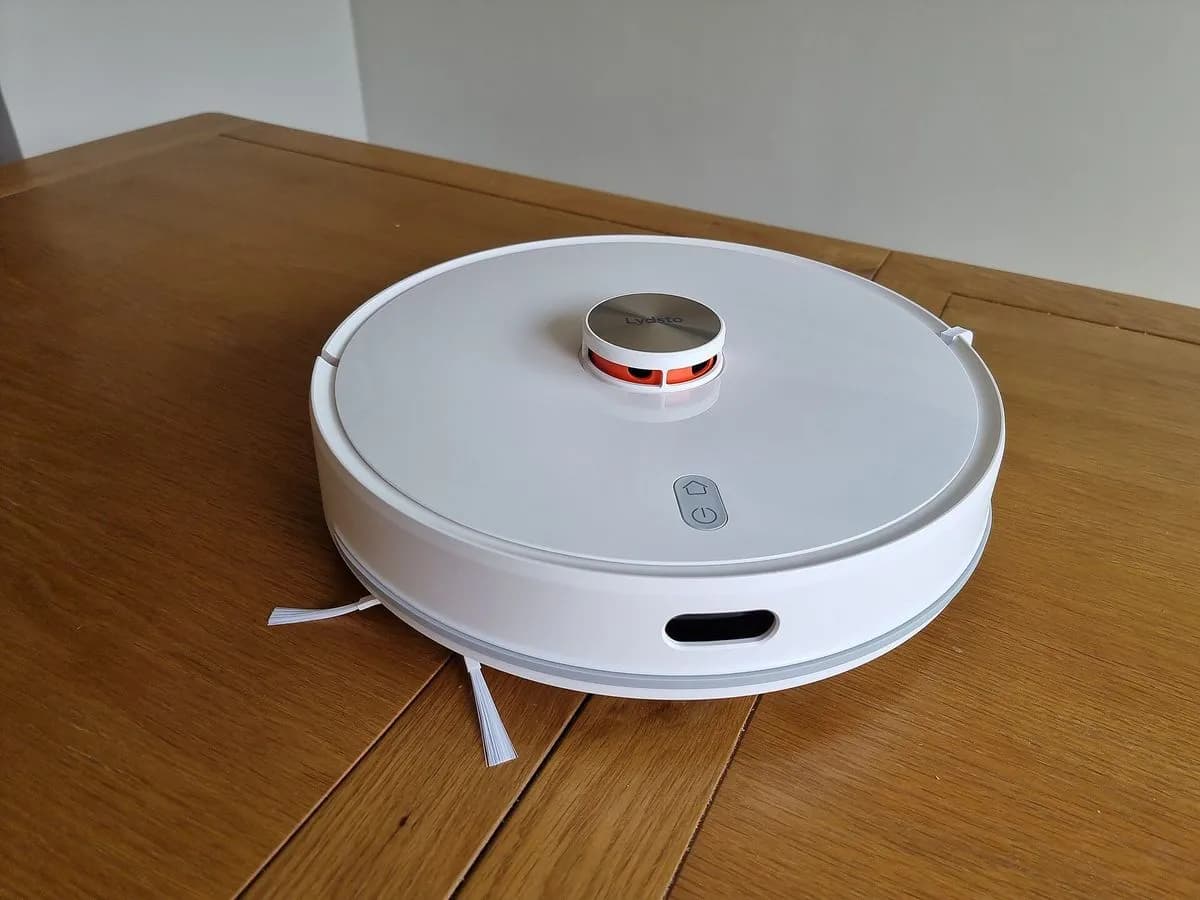 Robot aspirador redondo con sensor LiDAR sobre suelo de madera